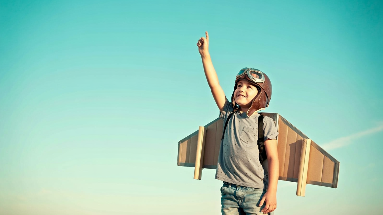 boy wearing a brown aviator helmet and a gray t-shirt, standing in a dramatic pose against a turquoise sky